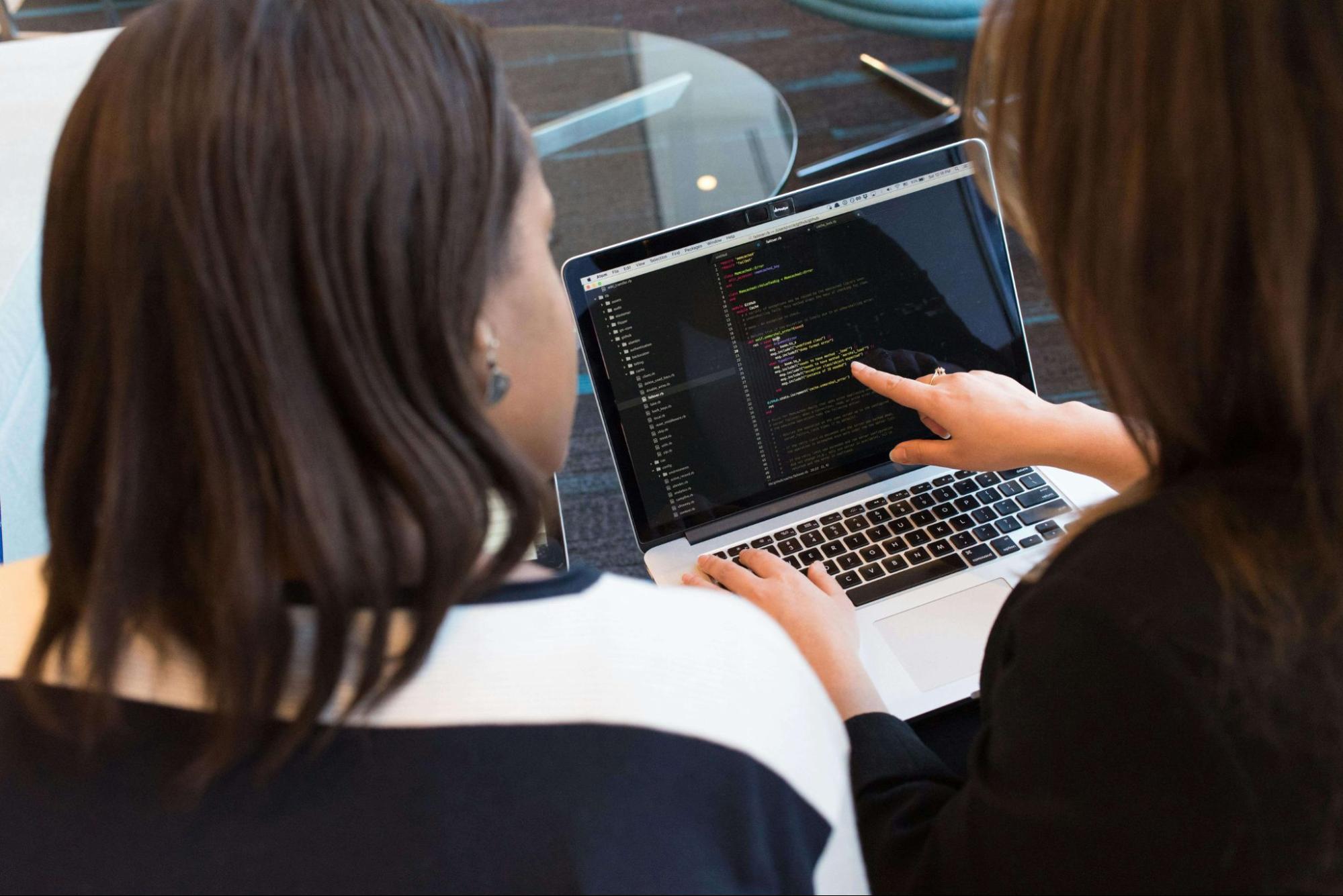 two people coding on laptop